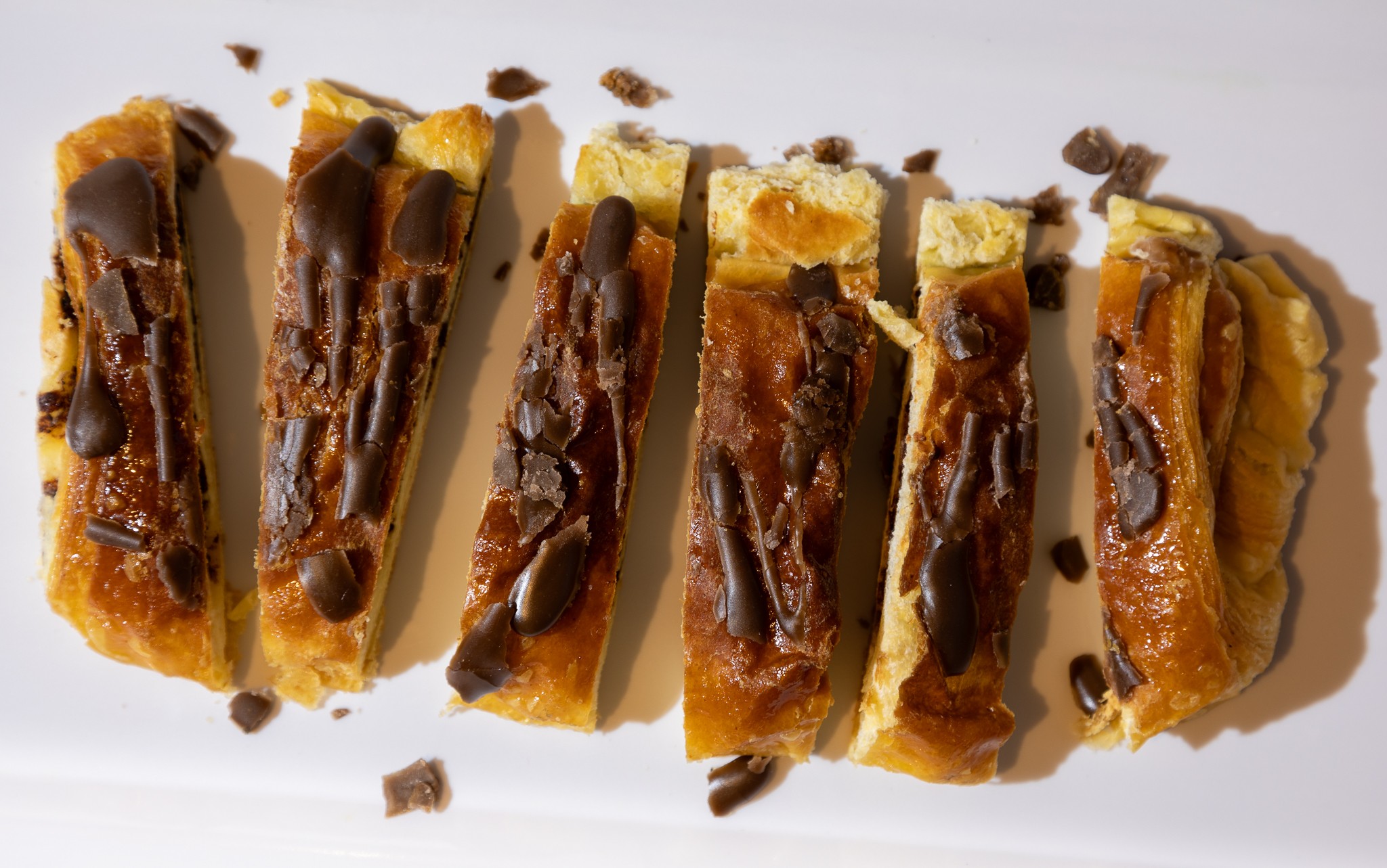 Flatlay photograph of Chocolate Croissant sliced on a white plate.