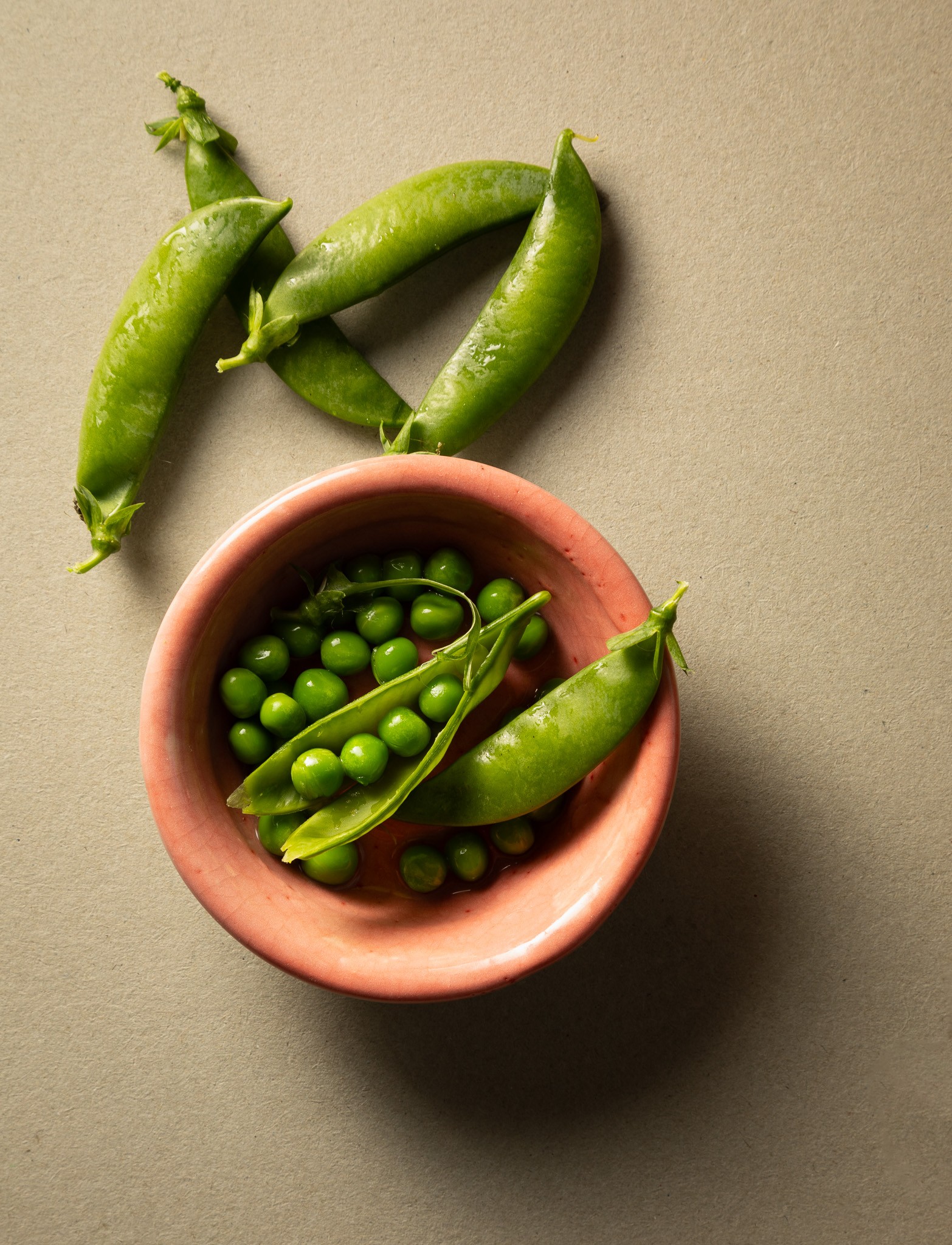 Photo of fresh green garden peas and pea pods in a salmon pink bowl.
Copyright Steve Wickenton Simply Food Phoitography