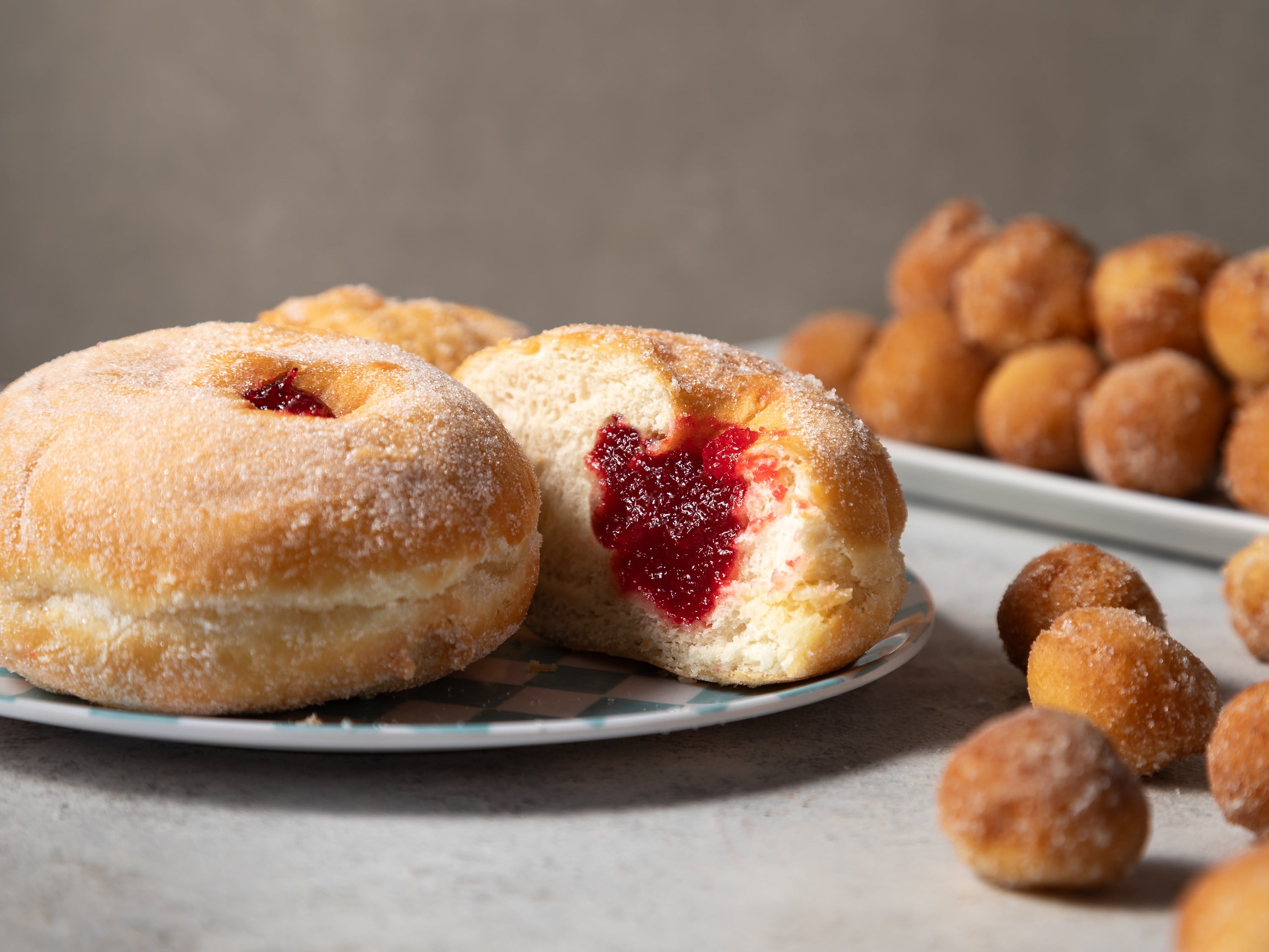 Jam donuts on a plate photographed with donut balls in open airy setting by Steve Wickenton